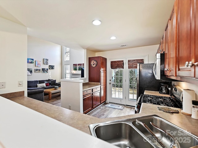 kitchen featuring appliances with stainless steel finishes, kitchen peninsula, sink, and light hardwood / wood-style flooring