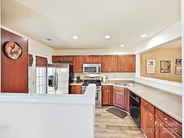 kitchen featuring appliances with stainless steel finishes, sink, and light hardwood / wood-style flooring