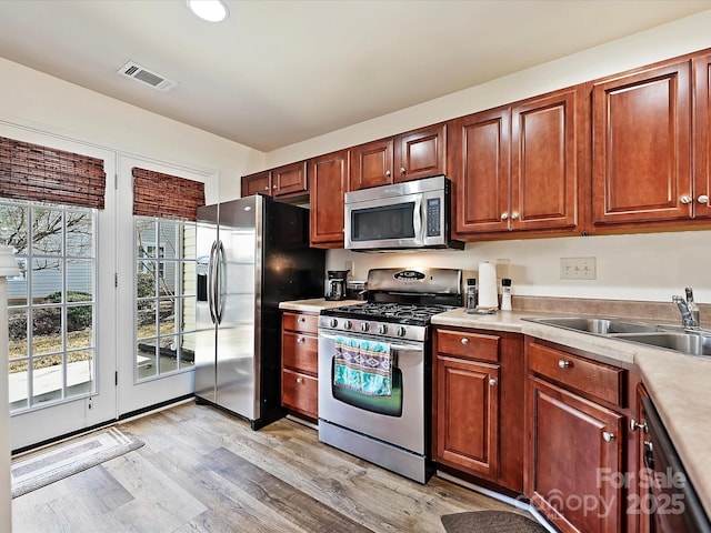 kitchen featuring stainless steel appliances, sink, light hardwood / wood-style flooring, and a wealth of natural light