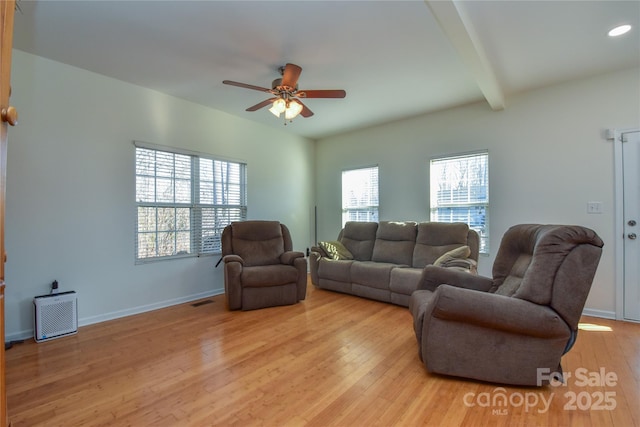 living room featuring light wood-style flooring, baseboards, ceiling fan, and beam ceiling