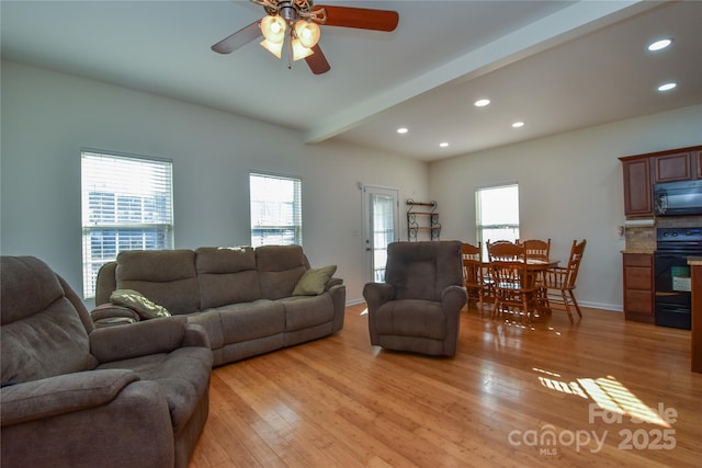 living room featuring a wealth of natural light, light wood-type flooring, beam ceiling, and recessed lighting