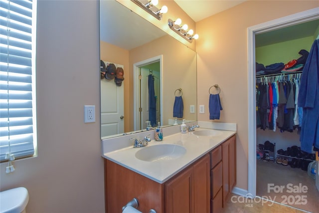 bathroom featuring a sink, a spacious closet, and double vanity