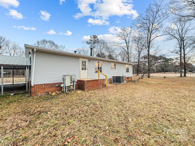 rear view of property featuring a lawn and central air condition unit