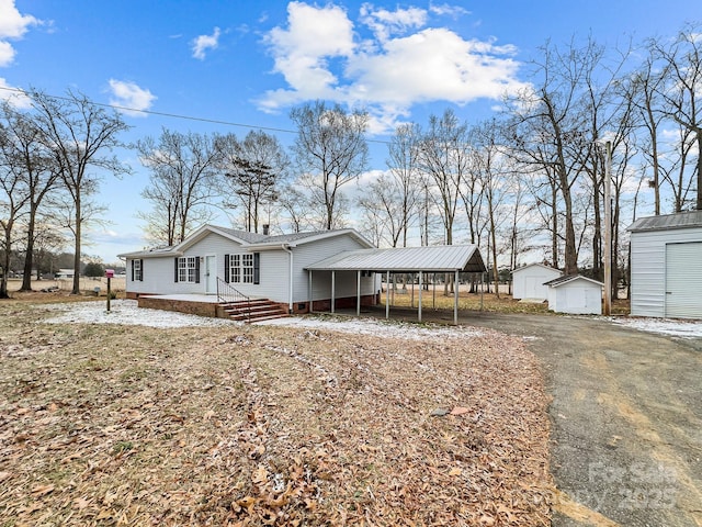 view of front of home with a carport and a shed