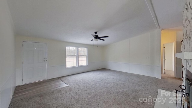 unfurnished living room with ceiling fan, carpet flooring, and a fireplace