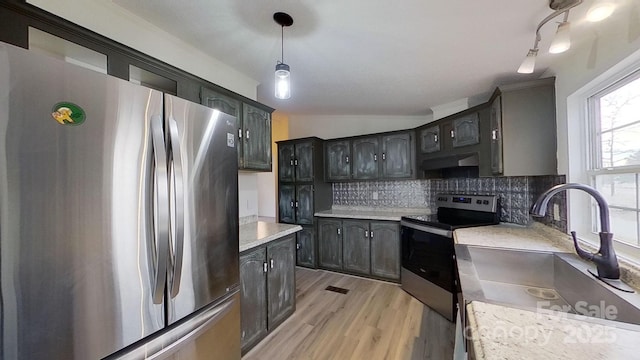 kitchen featuring sink, light hardwood / wood-style flooring, hanging light fixtures, stainless steel appliances, and tasteful backsplash