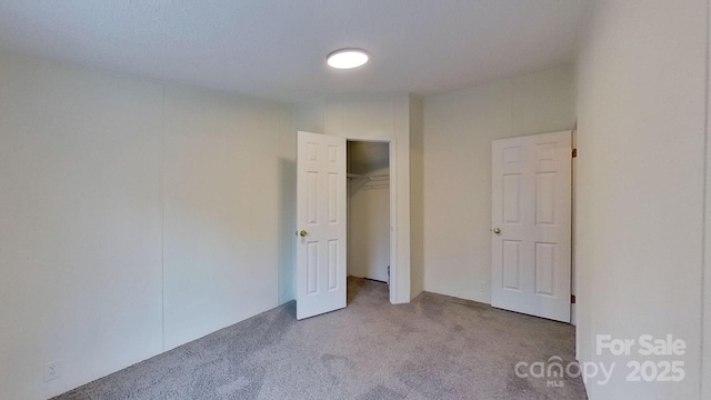 unfurnished bedroom featuring light colored carpet and a closet