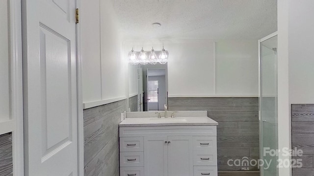 bathroom with vanity, wooden walls, and a textured ceiling