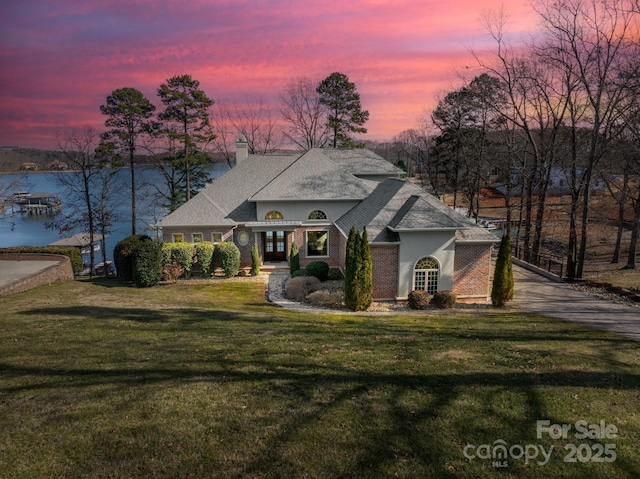 view of front of house featuring a water view and a lawn