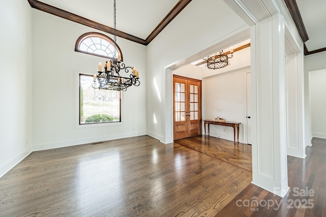 foyer entrance with an inviting chandelier, ornamental molding, dark hardwood / wood-style flooring, and french doors