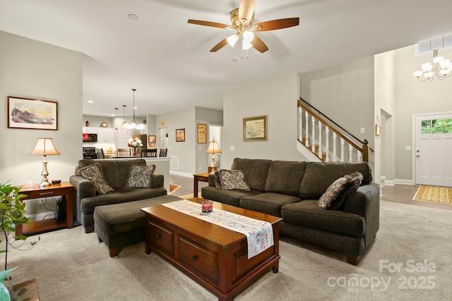 carpeted living room with ceiling fan with notable chandelier