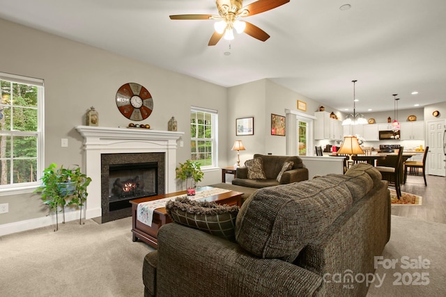 living room featuring light colored carpet and ceiling fan with notable chandelier