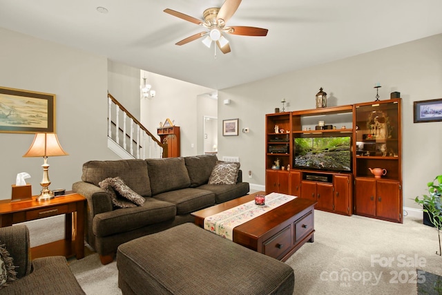 carpeted living room with ceiling fan with notable chandelier