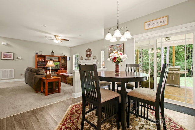 dining room featuring ceiling fan with notable chandelier, plenty of natural light, and light hardwood / wood-style floors