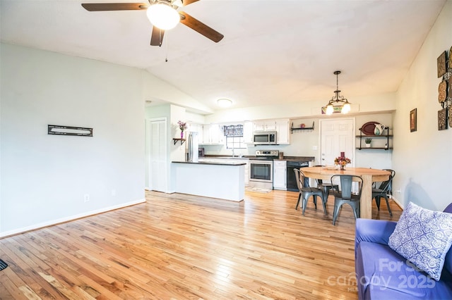 kitchen with hanging light fixtures, light hardwood / wood-style floors, white cabinets, and appliances with stainless steel finishes