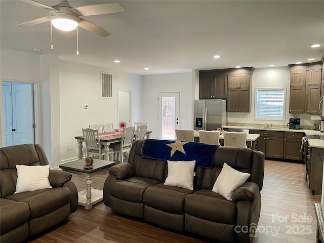 living room featuring sink, ceiling fan, and light hardwood / wood-style flooring