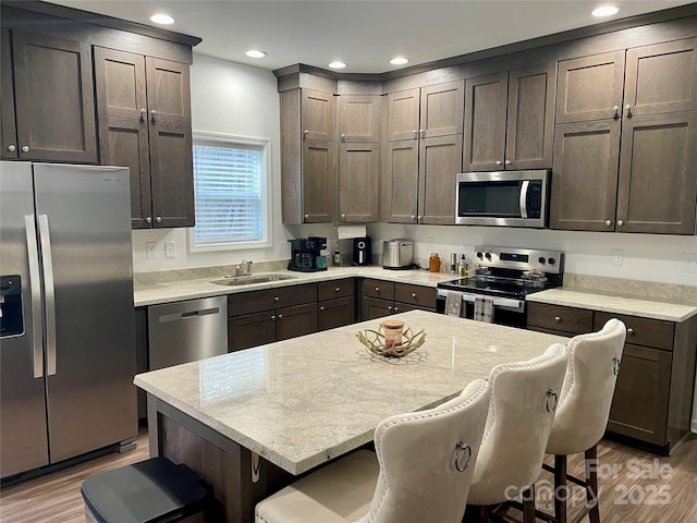 kitchen with appliances with stainless steel finishes, a breakfast bar, sink, and light wood-type flooring