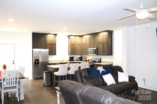 living room featuring ceiling fan and dark hardwood / wood-style flooring