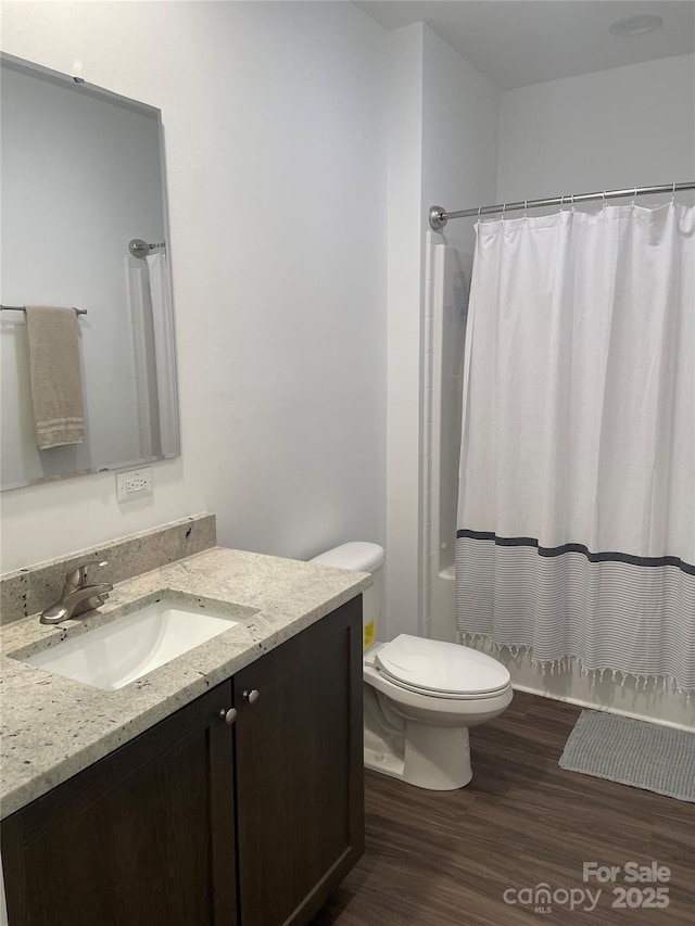 bathroom with hardwood / wood-style flooring, vanity, a shower with curtain, and toilet