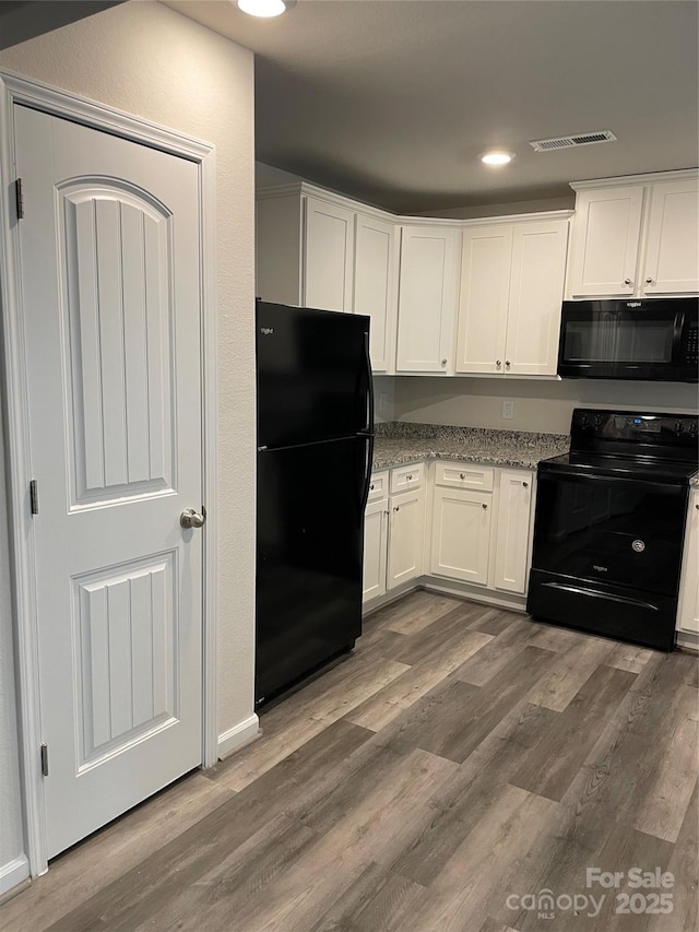 kitchen featuring black appliances, light stone counters, white cabinets, and dark hardwood / wood-style floors