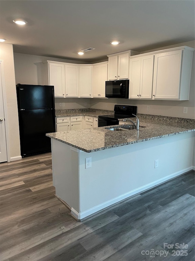 kitchen with black appliances, white cabinets, dark stone countertops, kitchen peninsula, and dark hardwood / wood-style flooring