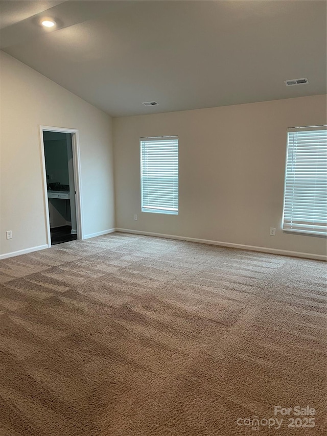 unfurnished room with plenty of natural light, carpet floors, and lofted ceiling