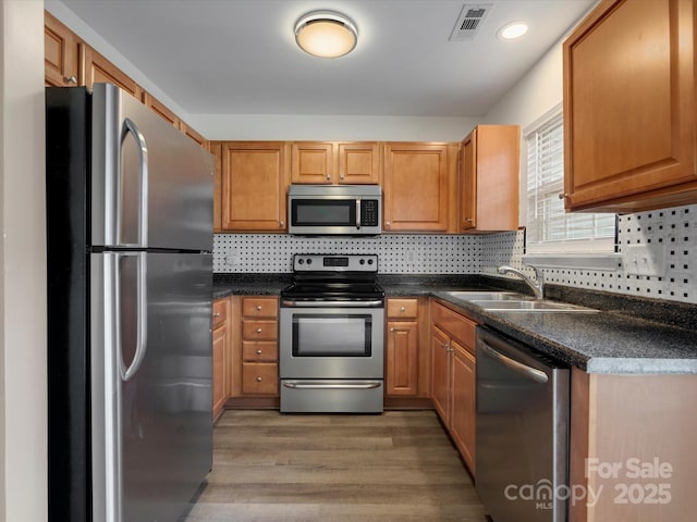 kitchen featuring tasteful backsplash, sink, wood-type flooring, and appliances with stainless steel finishes