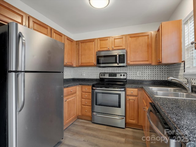 kitchen with tasteful backsplash, sink, hardwood / wood-style floors, and appliances with stainless steel finishes