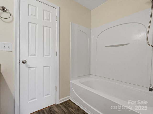 bathroom with hardwood / wood-style flooring and shower / washtub combination