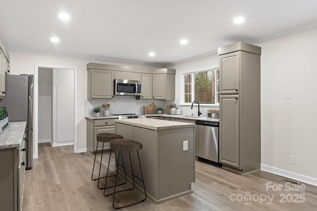 kitchen with sink, gray cabinets, appliances with stainless steel finishes, light hardwood / wood-style floors, and a kitchen island