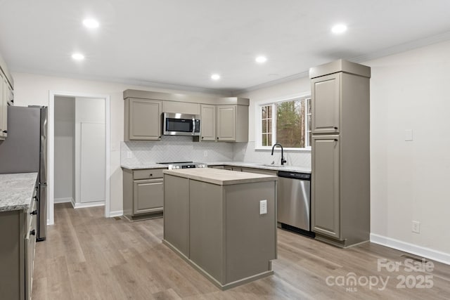 kitchen with gray cabinetry, light wood-type flooring, stainless steel appliances, and a kitchen island