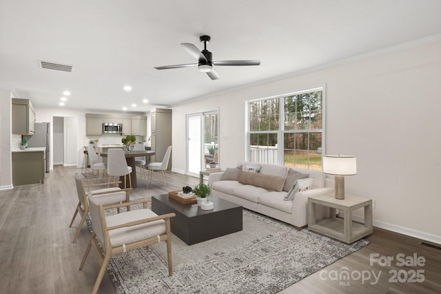 living room with hardwood / wood-style flooring, ceiling fan, and crown molding