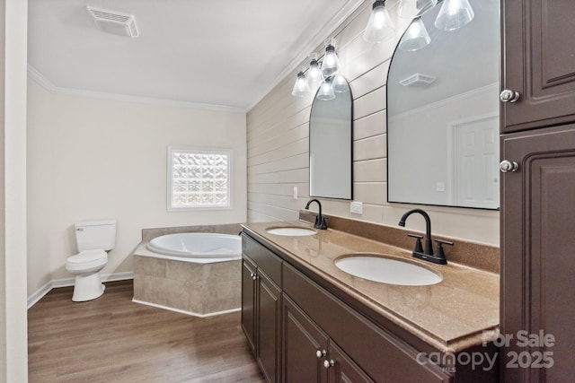 bathroom with toilet, ornamental molding, vanity, hardwood / wood-style flooring, and tiled bath