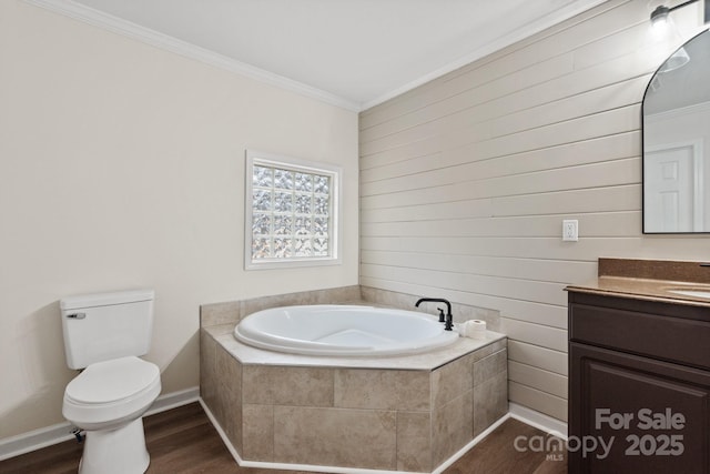 bathroom featuring toilet, wood-type flooring, ornamental molding, vanity, and a relaxing tiled tub