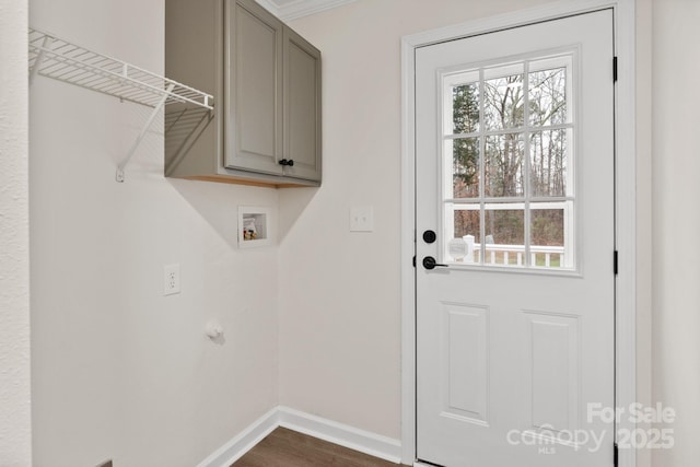 laundry area featuring hookup for a washing machine, dark wood-type flooring, ornamental molding, and cabinets