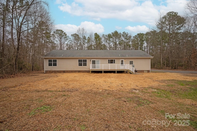 rear view of property featuring a wooden deck and a lawn