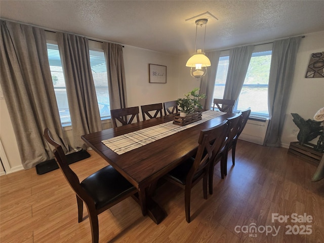 dining space with hardwood / wood-style flooring and a textured ceiling