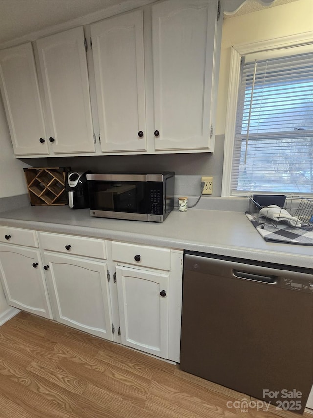 kitchen with appliances with stainless steel finishes, white cabinets, and light hardwood / wood-style flooring