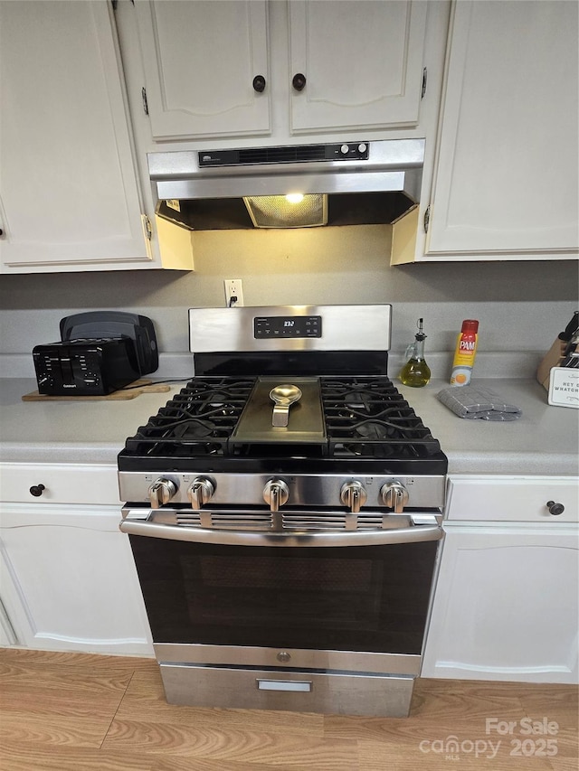 kitchen with stainless steel range with gas stovetop and white cabinets