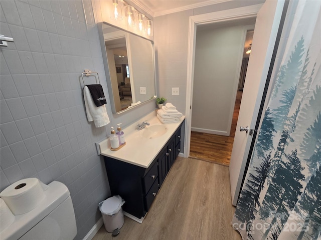 bathroom featuring tile walls, hardwood / wood-style floors, vanity, ornamental molding, and toilet