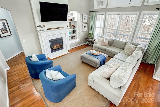 living room with hardwood / wood-style flooring, a fireplace, and built in shelves