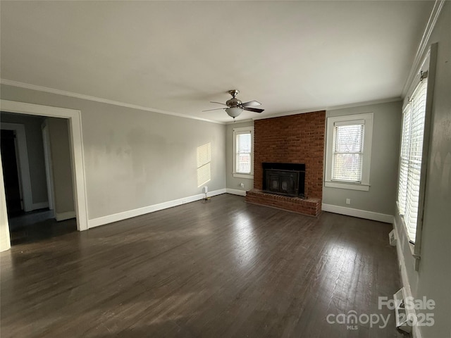 unfurnished living room with crown molding, a brick fireplace, dark hardwood / wood-style floors, and ceiling fan