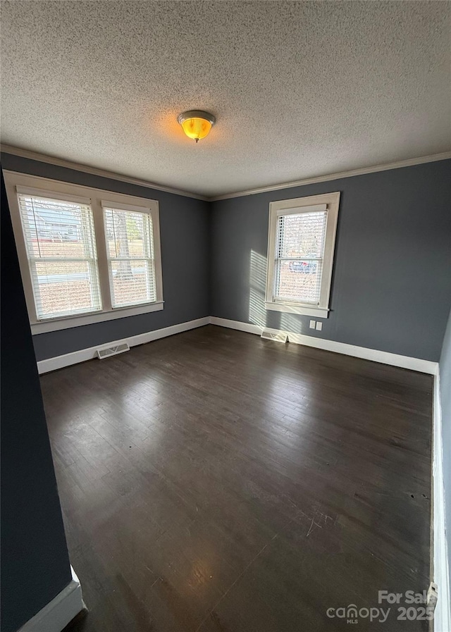 spare room featuring crown molding, dark hardwood / wood-style floors, and a textured ceiling