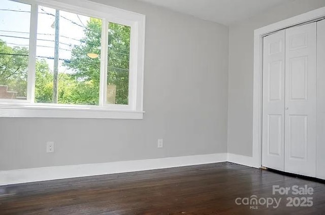 unfurnished bedroom with dark hardwood / wood-style floors and a closet