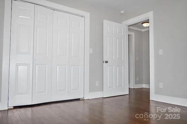 unfurnished bedroom with dark hardwood / wood-style floors and a closet