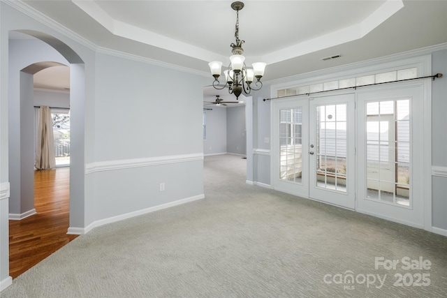 unfurnished room featuring ornamental molding, light colored carpet, a raised ceiling, and a chandelier