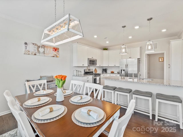 dining area featuring ornamental molding, dark hardwood / wood-style flooring, and sink