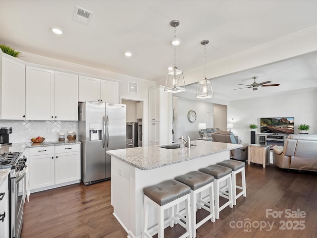 kitchen featuring white cabinetry, stainless steel appliances, an island with sink, and pendant lighting