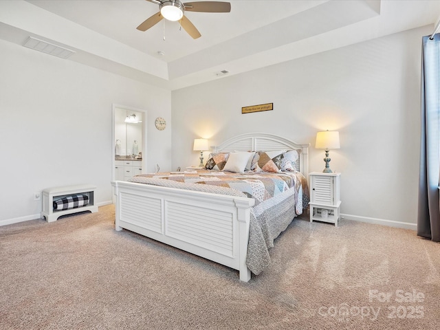 bedroom with carpet flooring, connected bathroom, ceiling fan, and a tray ceiling