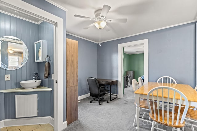 dining area featuring ceiling fan, ornamental molding, sink, and carpet